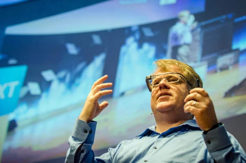 man with glasses on at a podium giving a presentation