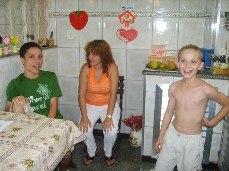 three people are standing in front of a kitchen table