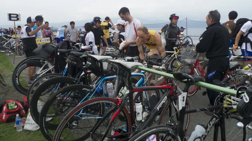 the people are gathered next to the parked bikes