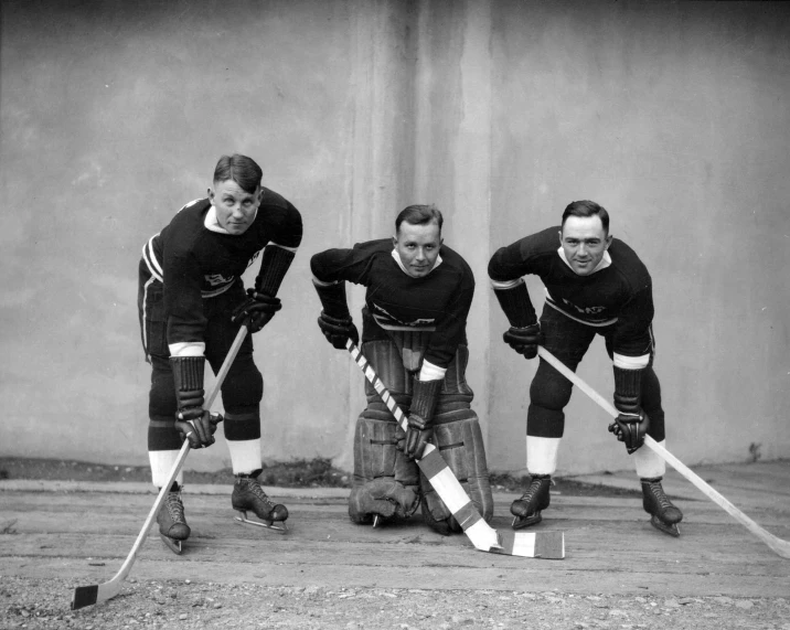three hockey players pose with their stick and uniform