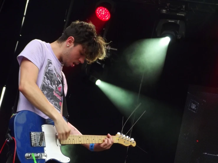 man plays guitar while on stage at concert