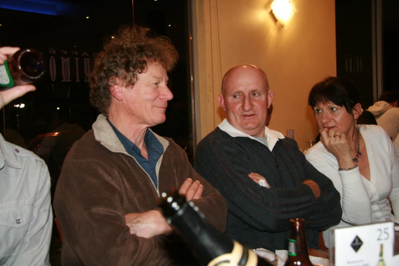 three people are standing with their arms crossed