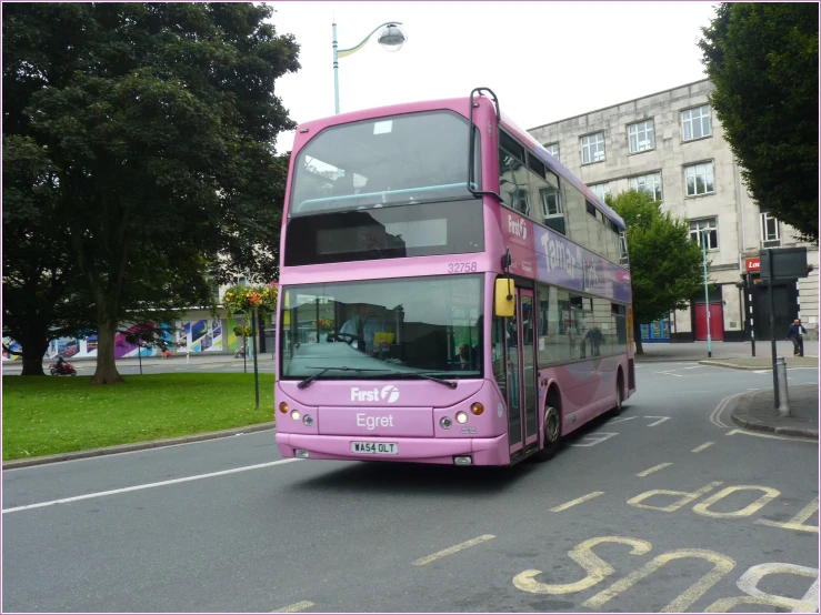 pink double decker bus traveling down the street