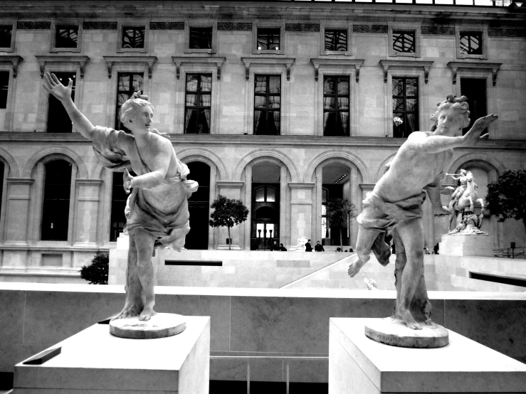 black and white pograph of two statues of men in front of a building