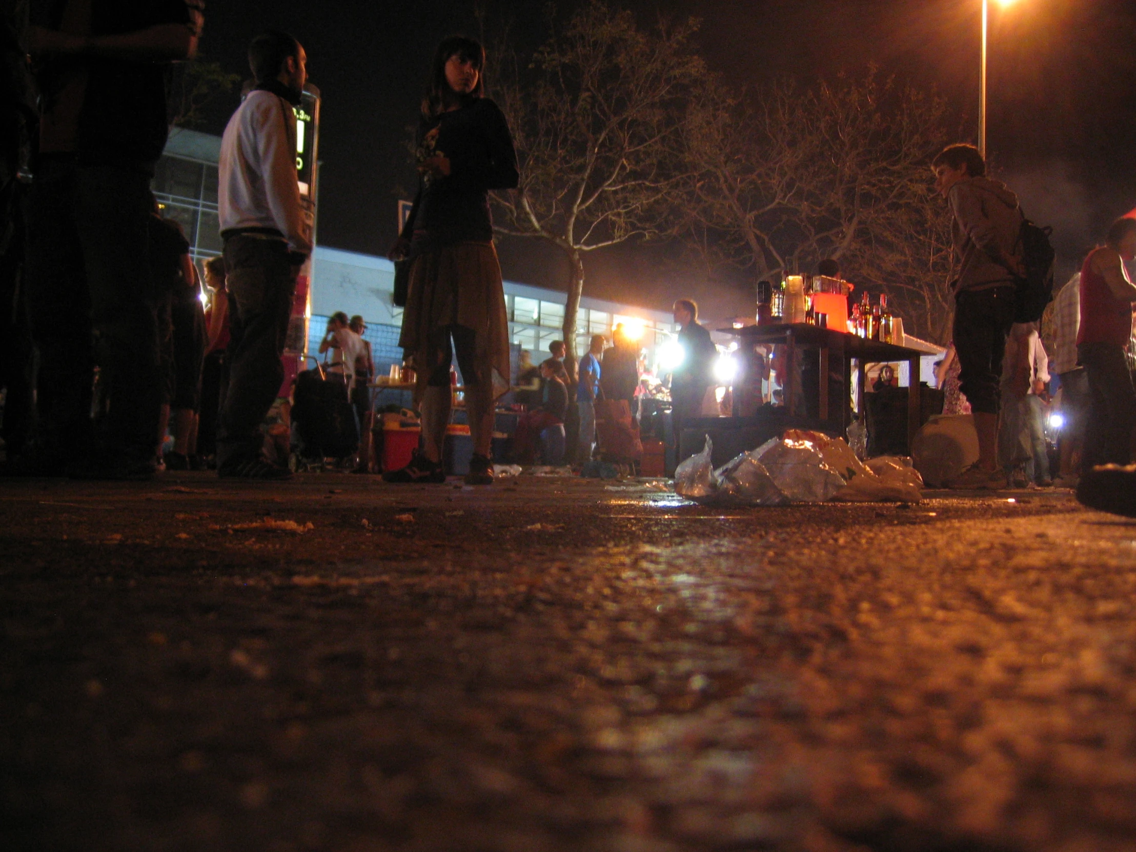 people stand on the side of the road next to some garbage