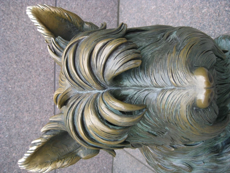 a bronze sculpture of a dog's head on a sidewalk