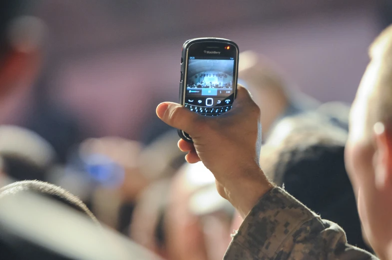 a person is holding up his cell phone in the air