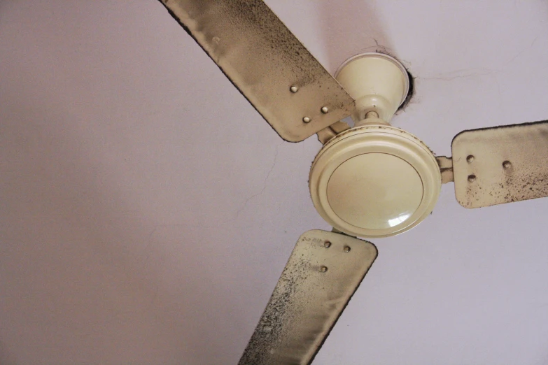 an old and dirty ceiling fan with holes on it
