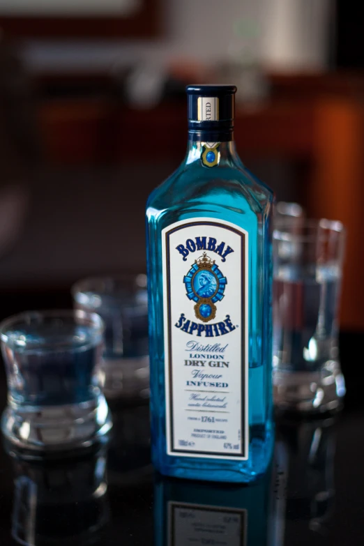 an empty blue bottle on a table with several s glasses