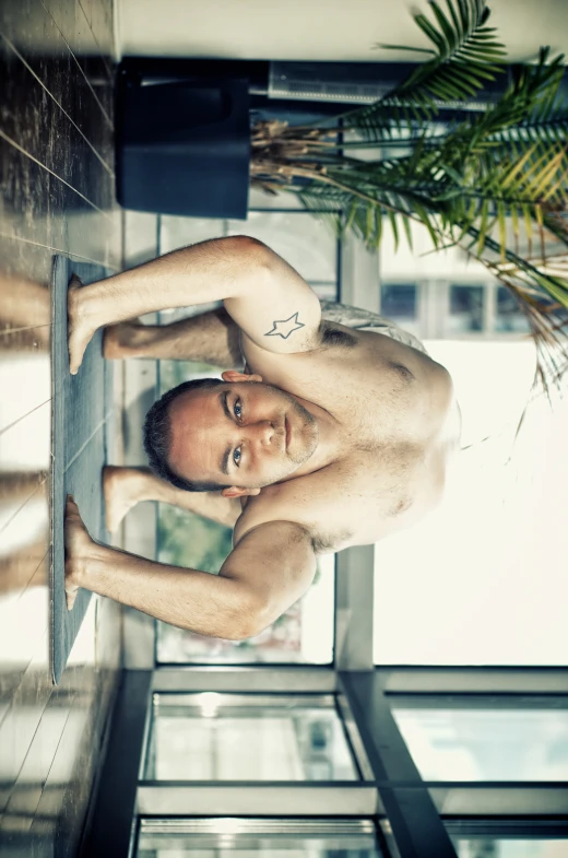 a shirtless man leaning on the side of a window