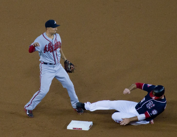 the baseball player slides into the base while another player slides towards base