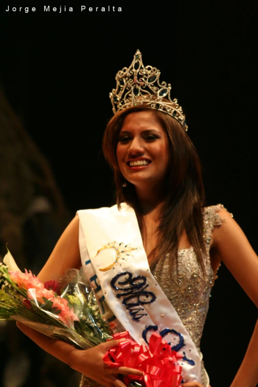 a young woman standing on top of a stage holding a bouquet