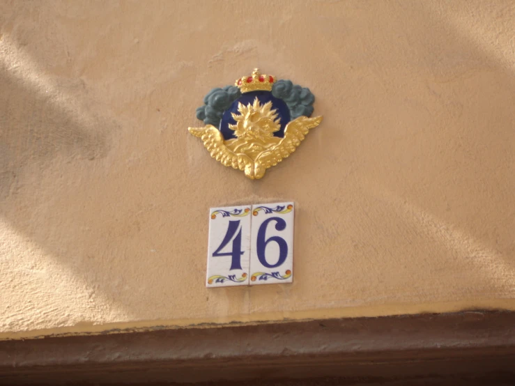 the golden sign on a tan wall features a blue crown and gold frame