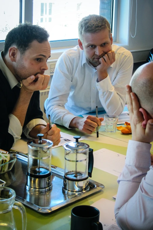 men seated around table talking with one another