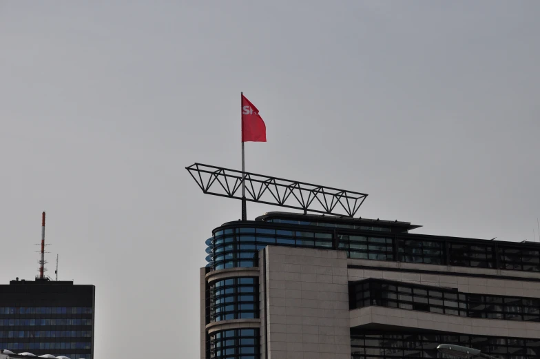 a red flag on top of a building in a cloudy sky