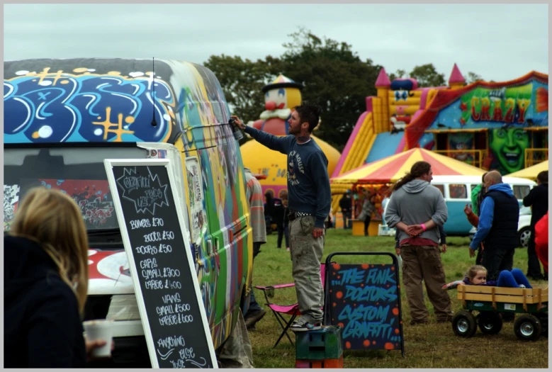 people standing near a chalk board sign in a field