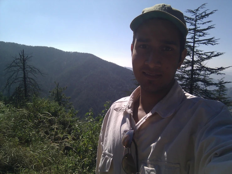 a man in a hat and shirt standing on top of a hill