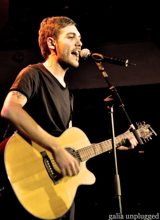 the man is singing into his microphone and playing the guitar