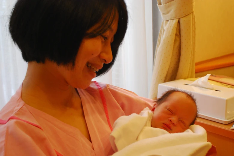 a woman holds a baby in a pink shirt