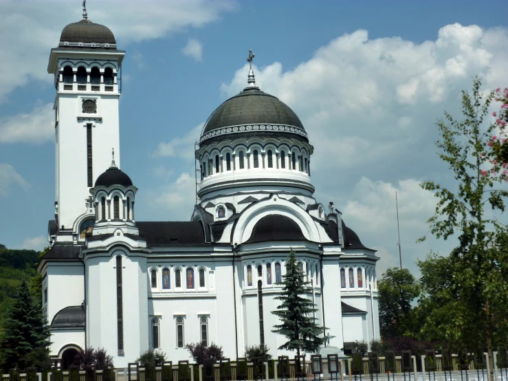 two towers and one dome on a building with a fence in front