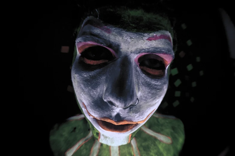 a man in clown makeup looks up at the camera