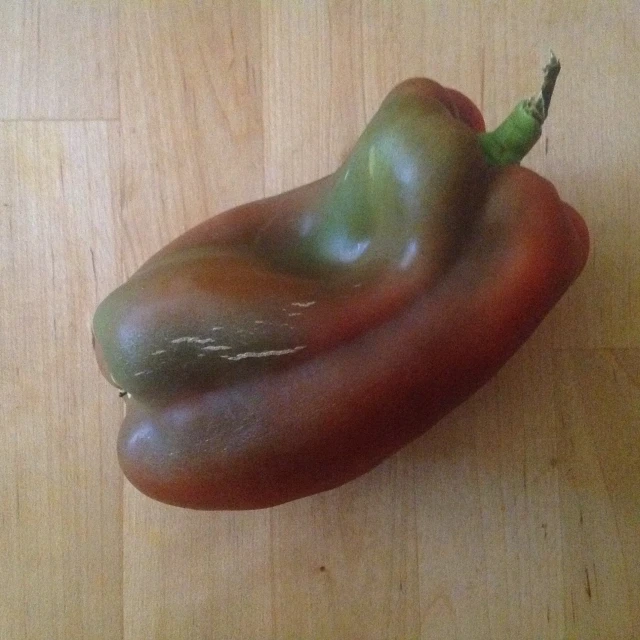 two long bell peppers sitting on a wooden table