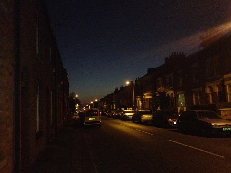 dark and empty city street at night with cars in foreground