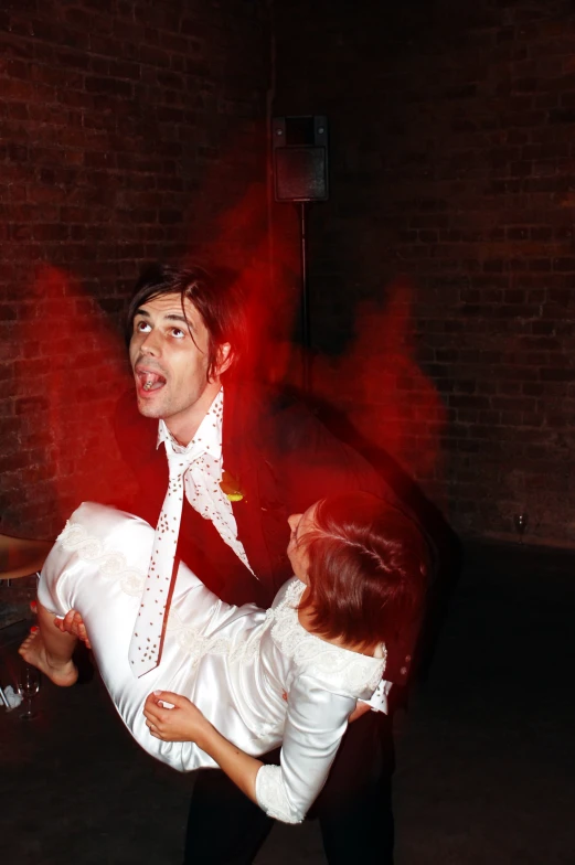 man in red tie and white shirt holding onto a lady