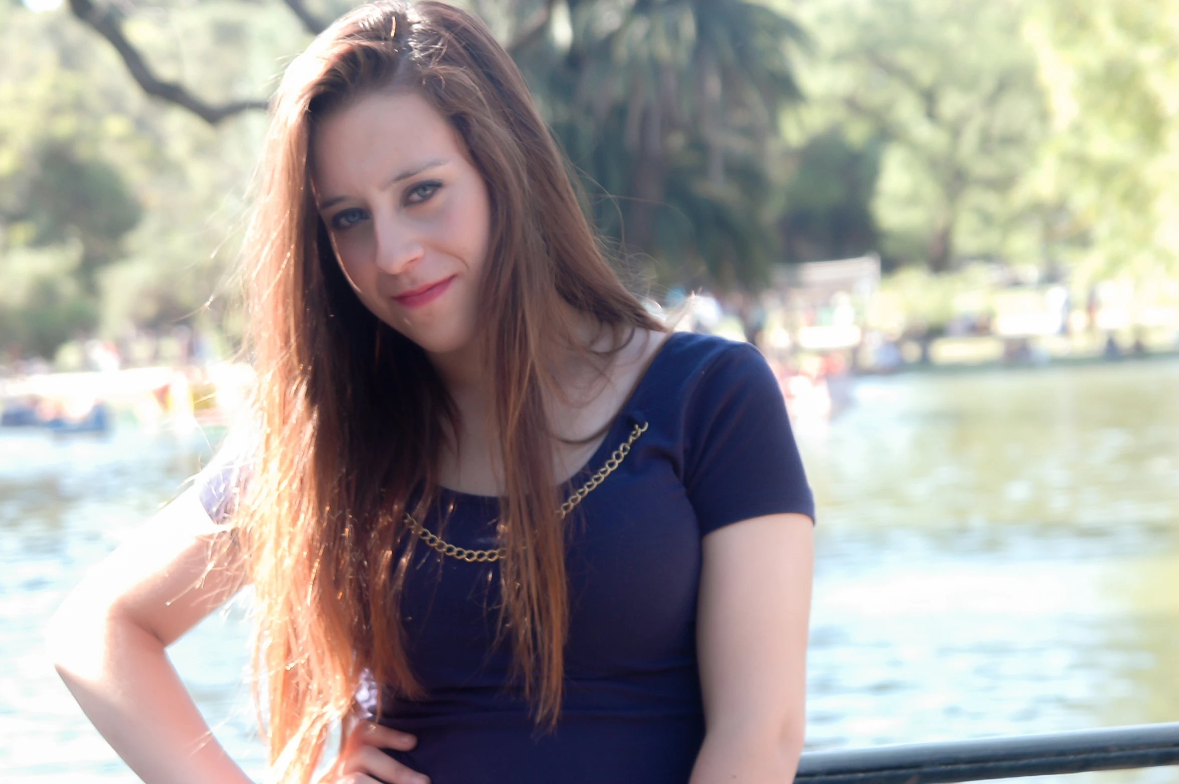 a beautiful young woman with long brown hair standing by a lake