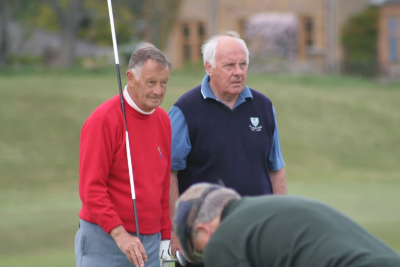 two men in polo attire holding a golf club