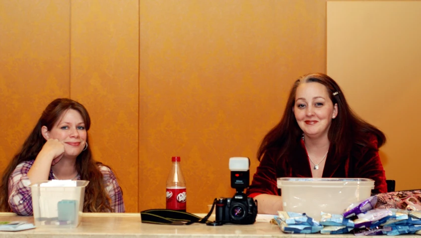 two women sitting at a table with food and drinks