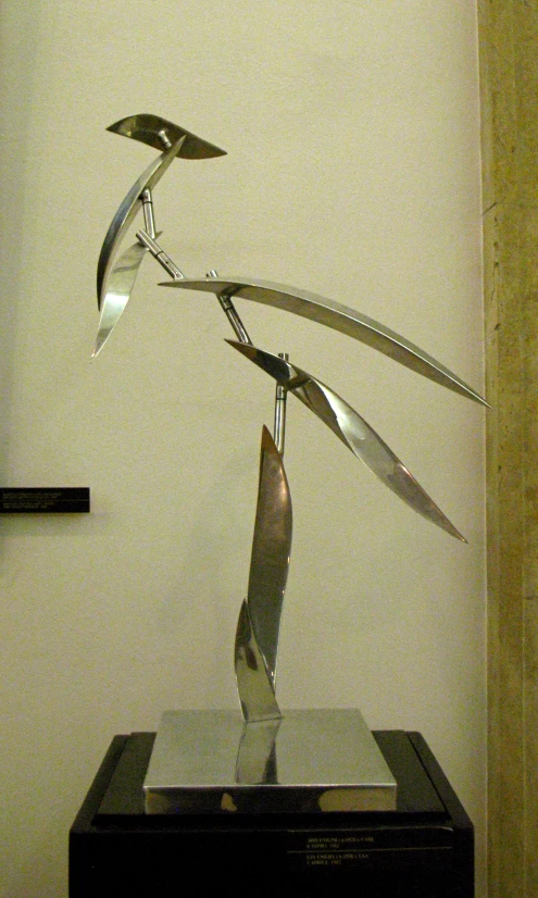 a metal sculpture holding scissors on a clear display stand