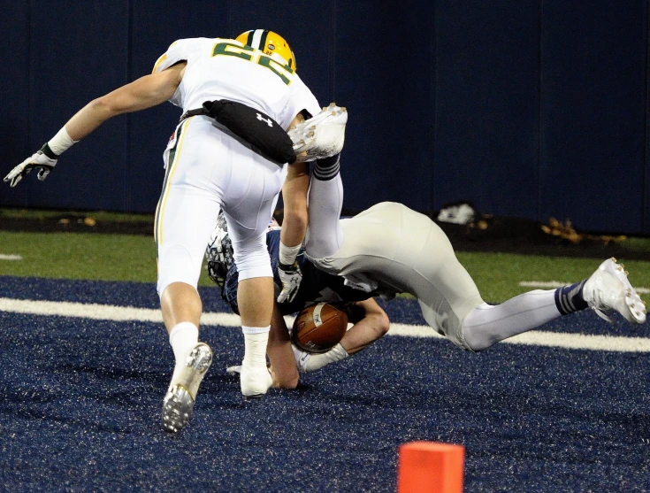 a football player on his feet being tackled by an opposing teammate