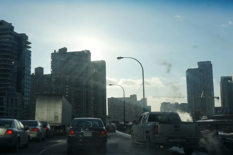 several cars stopped at a traffic light near skyscrs