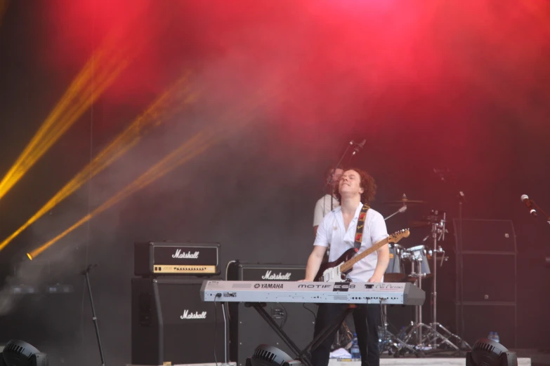 a person standing next to a keyboard on top of a stage