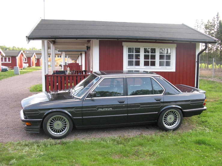 a black car is parked near a red house