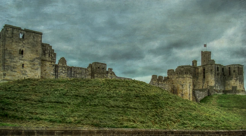 castle like structure atop a grassy hill with a clock in the background