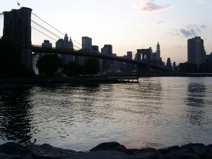 there is a boat in the water near a large bridge