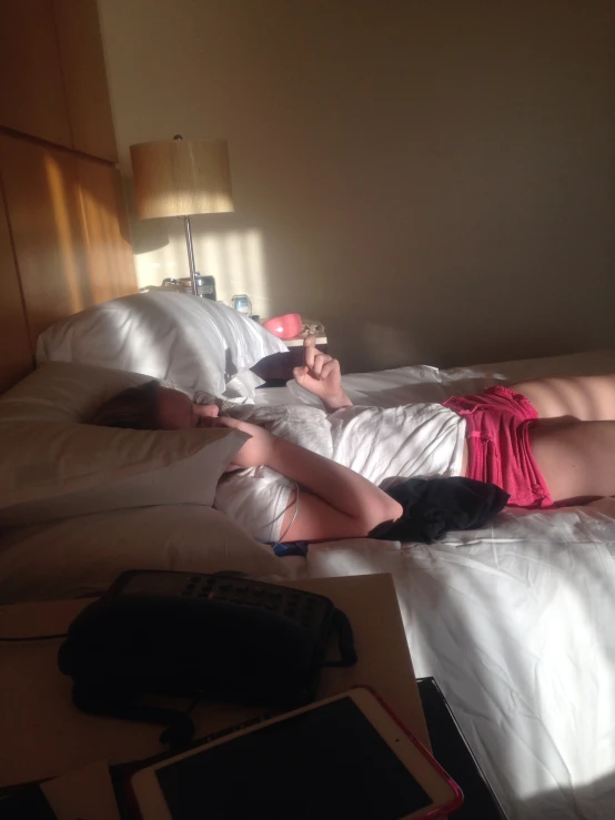 a woman laying in bed looking at her cell phone