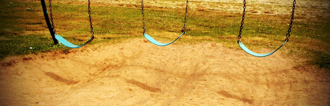 a grassy field with three swings in the middle