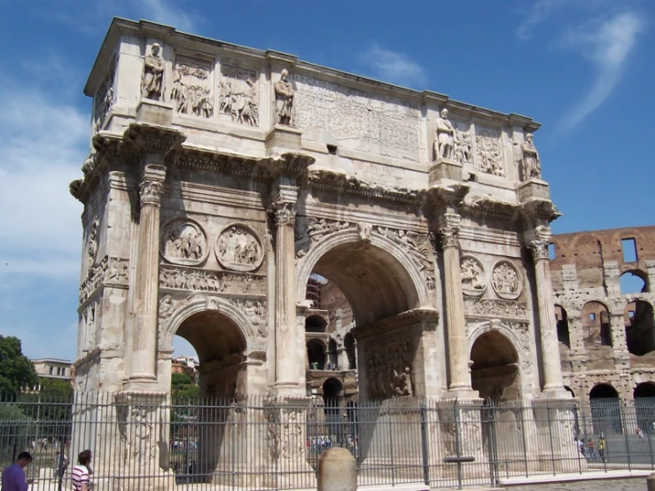 two people walk by an arch with carvings on it