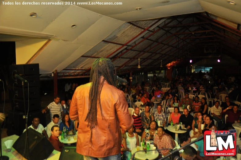 a large crowd watching a man singing in front of a room full of people