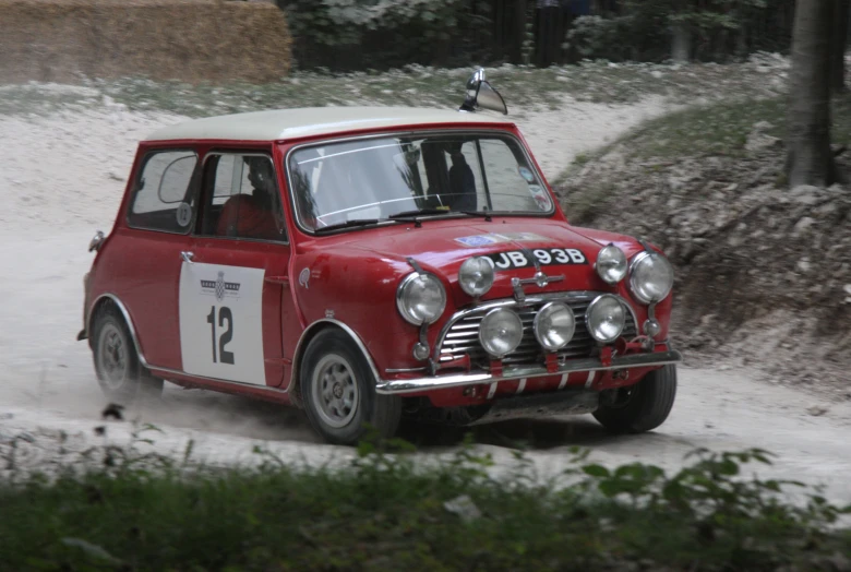 an older mini car driving down the snowy road