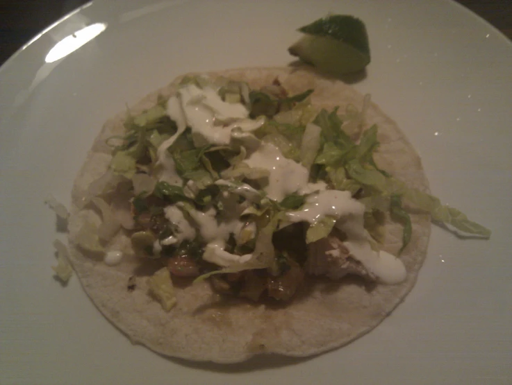 a taco on top of a white plate on a table