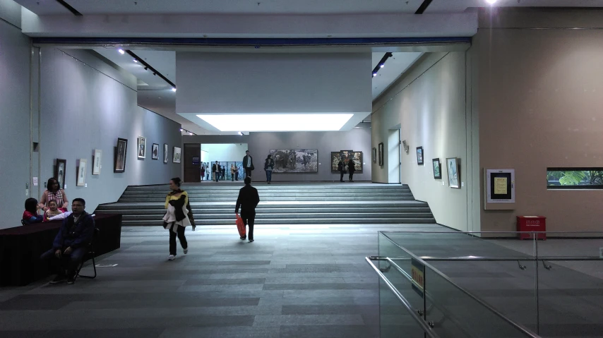 a group of people walking in a museum with multiple sets of staircases