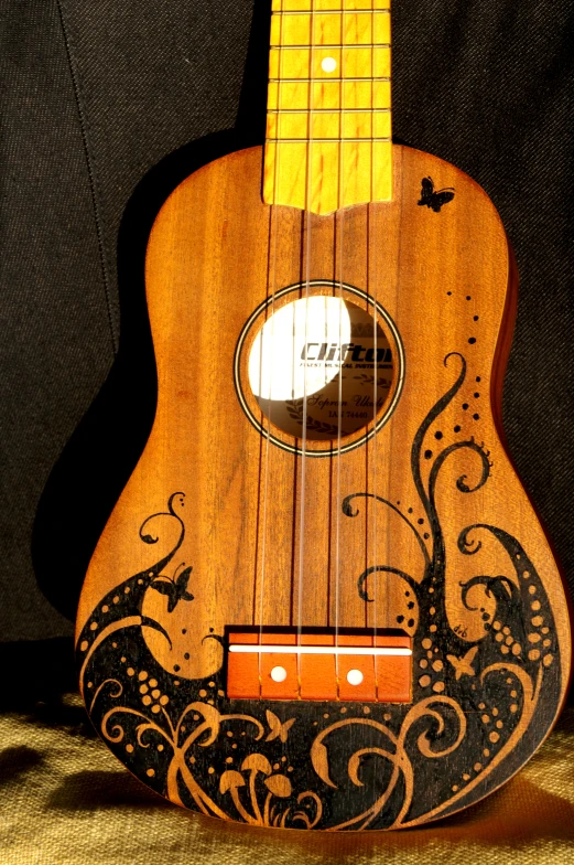 a brown and black instrument with intricate carving on the body