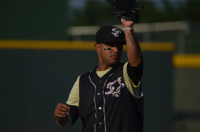 a man in uniform holds his glove while wearing a hat