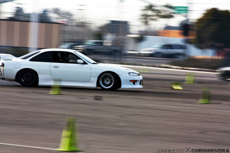 a white car driving through cones on top of a track