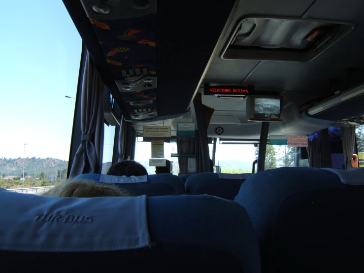 the interior of a large bus with several blue seats and no people