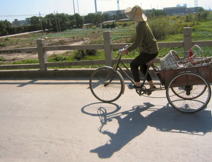 woman on a bike with a basket riding along the side of the road